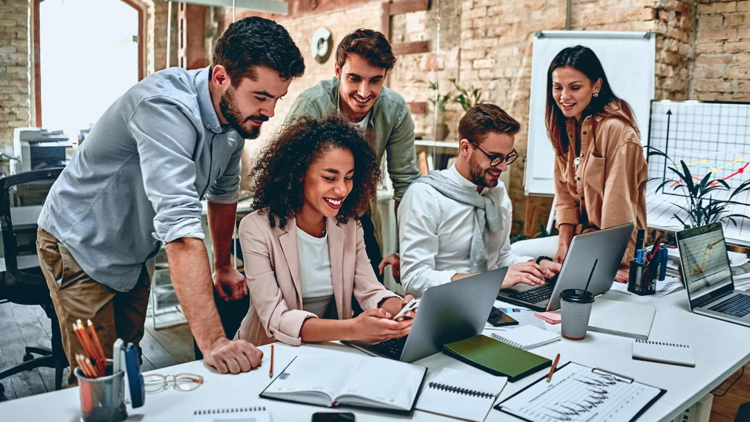 Business team collaborating in a modern office using laptops and mobile devices while reviewing digital information together