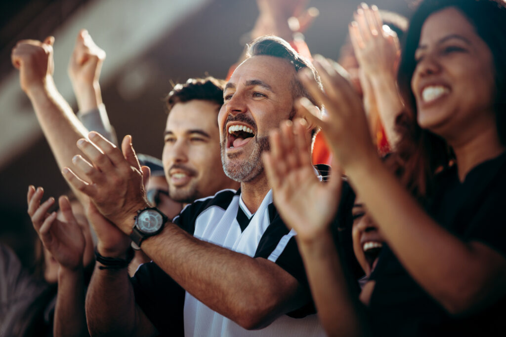 Community members cheering together at an event, representing connection and shared experiences